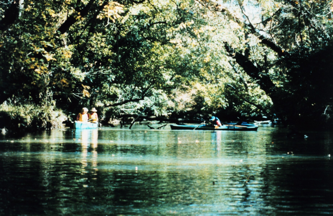 Canoers and kayakers enjoying an idyllic early fall afternoon on a quiettree-lined stretch of the upper Patuxent River
