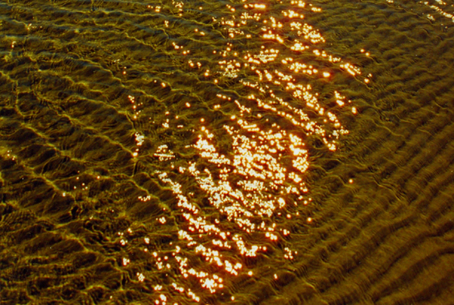 The swash zone at Nanny Goat Beach showing ripple pattern in sand and sunlightreflecting off the water