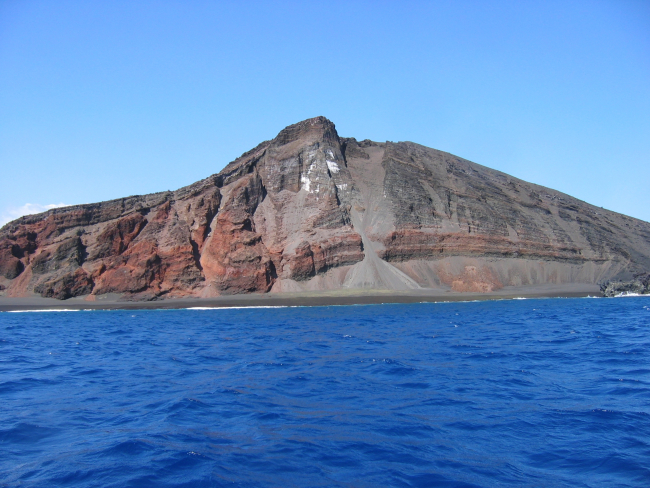 Interior structure of an eroded volcanic cone where it meets the sea