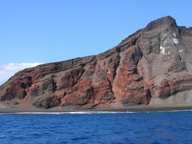 Interior structure of an eroded volcanic cone where it meets the sea