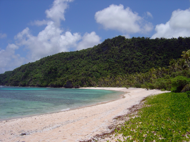 An arcuate deserted beach on Guam with calm warm inviting waters