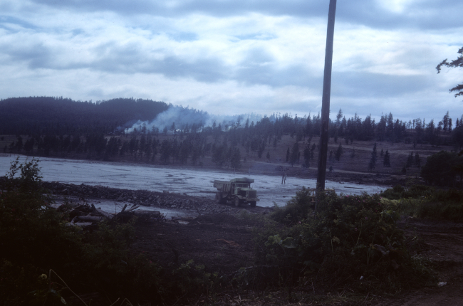 Burning brush on hillside, dump truck filling in tidal wetland area