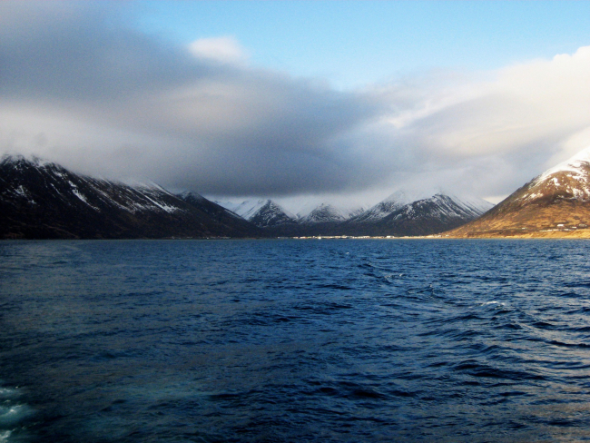 Departing King Cove with cloud shrouded, snow covered mountains in distance