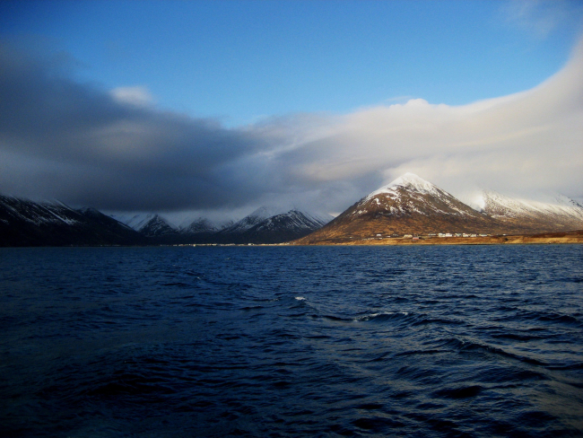 Departing King Cove with cloud shrouded, snow covered mountains in distance