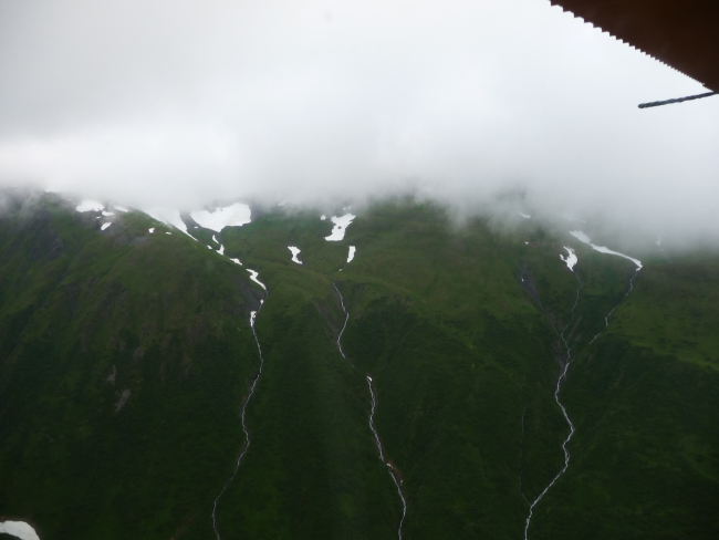 Aerial view of silver ribbons of falling water trickling to the sea
