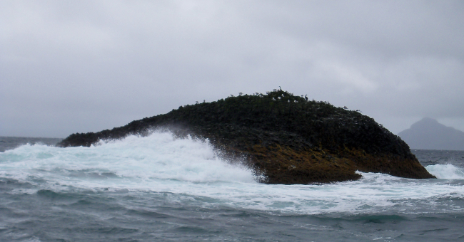 Surf washing an outlying rock along the Alaska coastline