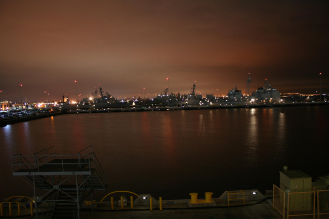 The lights of San Diego silhouette naval ships at 32nd Street Naval Base