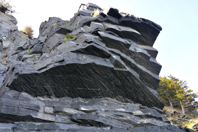 Where the sea ends on the banded rock cliffs of Kodiak Island