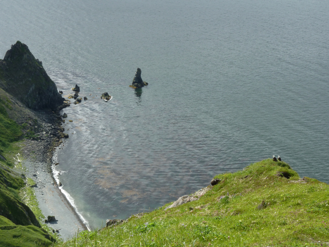 Looking down from a high cliff to a small beach in the Dutch Harbor area